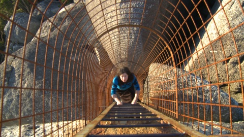 Woman climbing up cage at Castle Rock